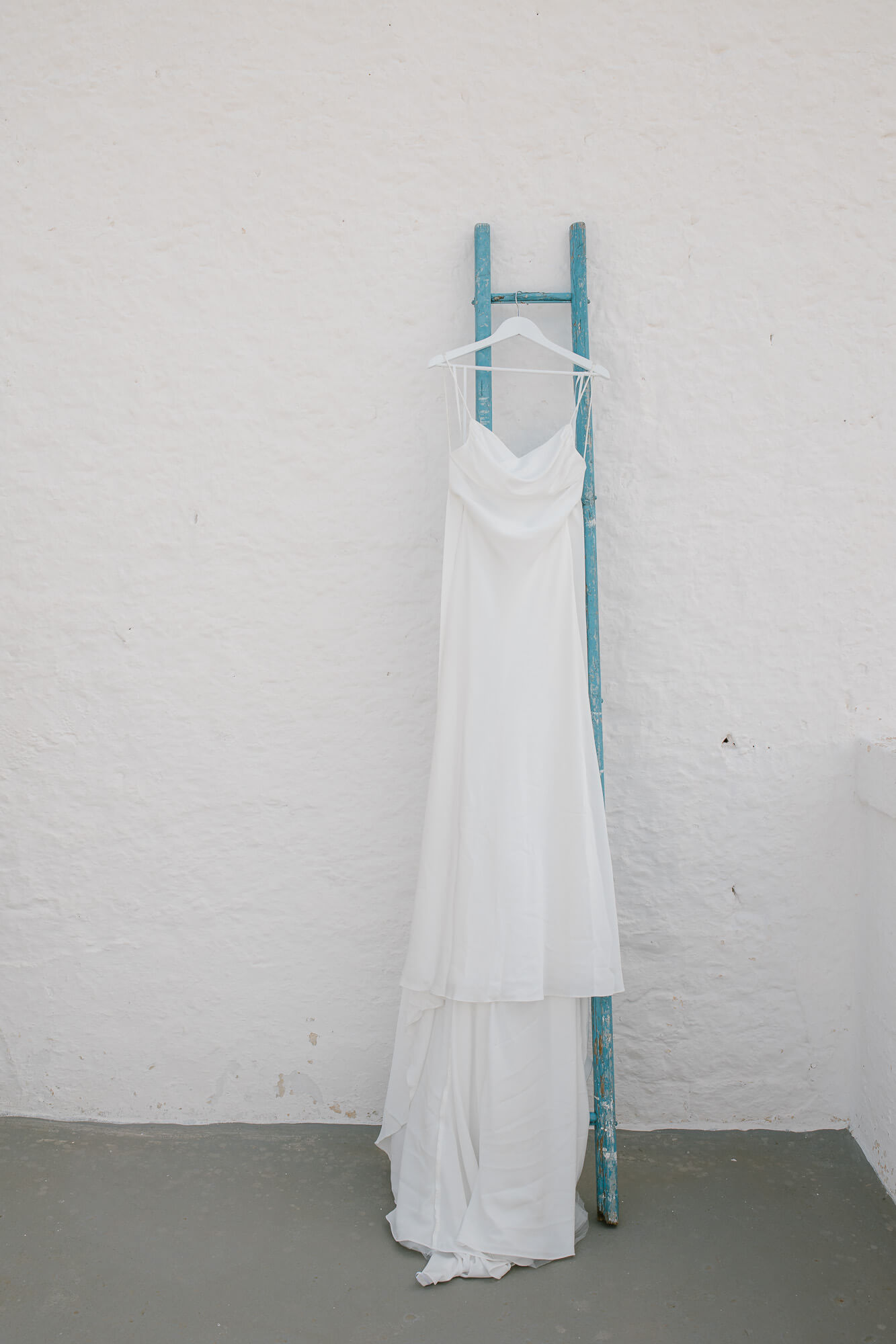 Wedding dress hanging against a whitewashed wall