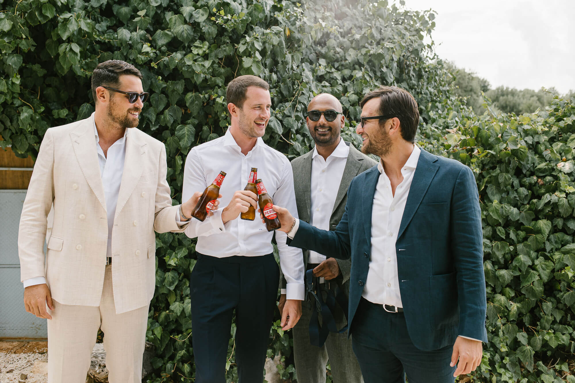 Groom and groomsmen sharing a beer before the wedding