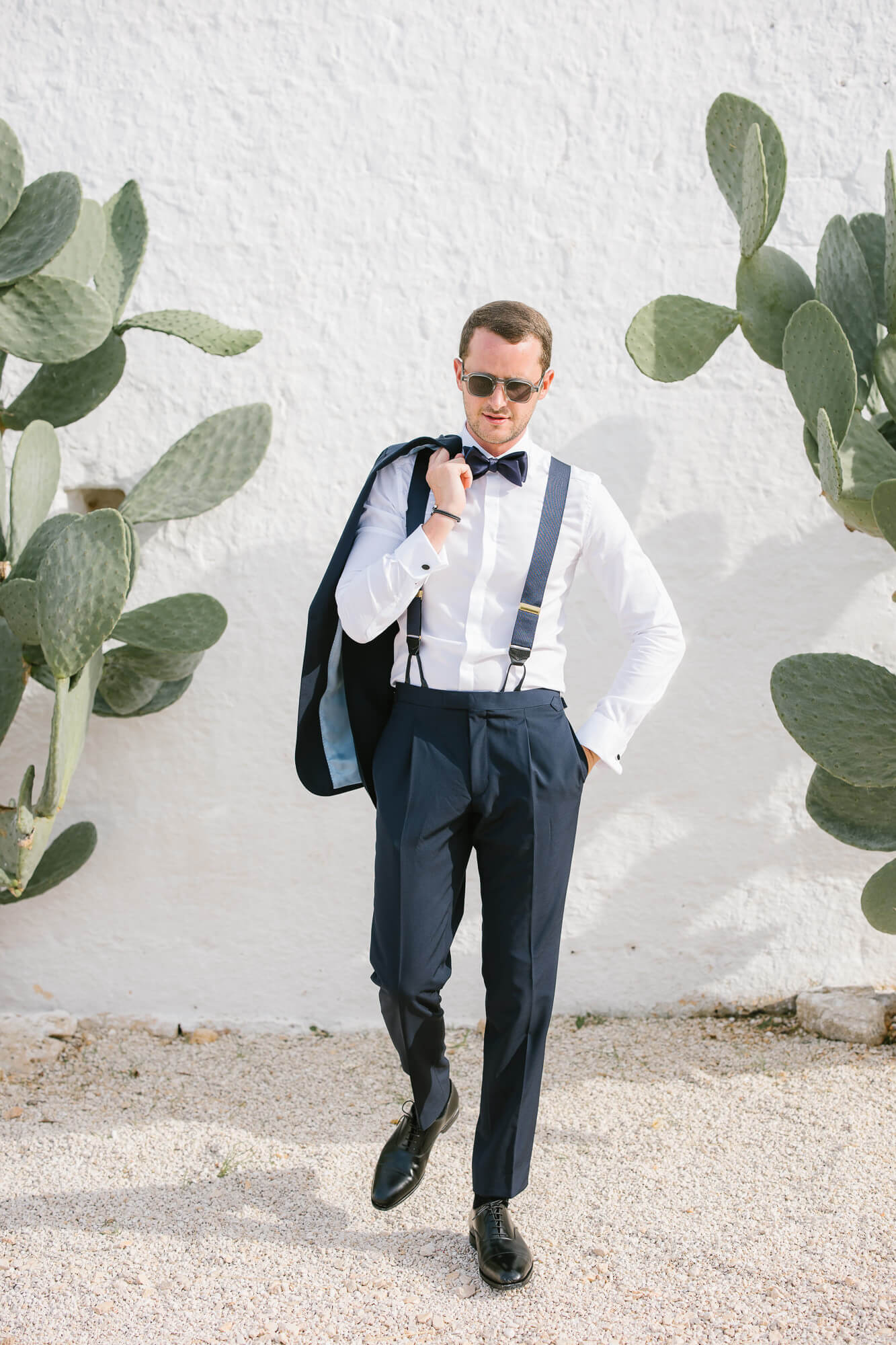 Groom with his jacket over his shoulder between prickly pears at Masseria Mozzone