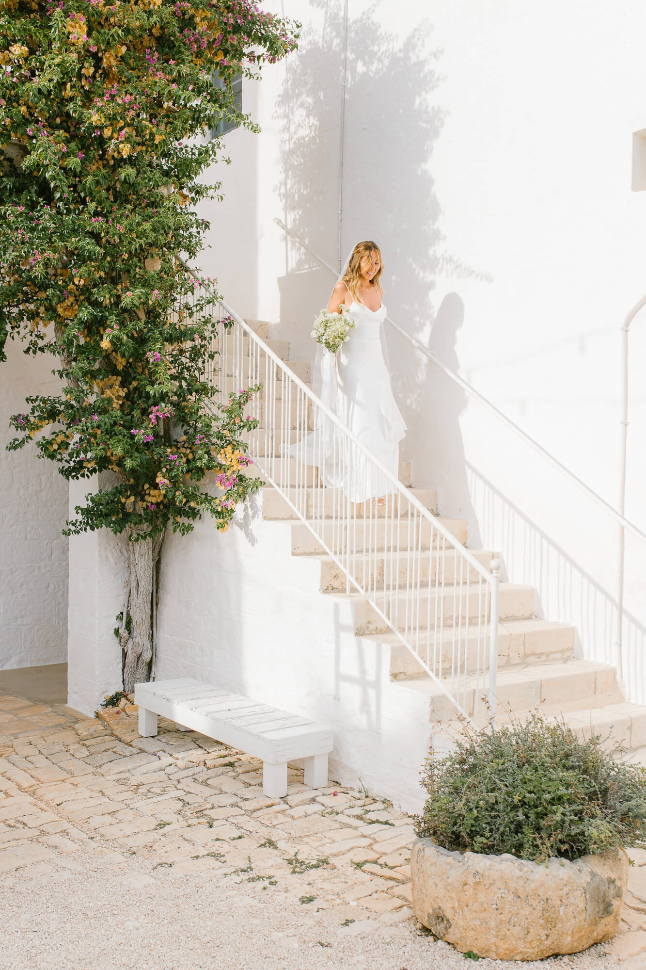 Bride by the whitewashed staircase with bougainvillea