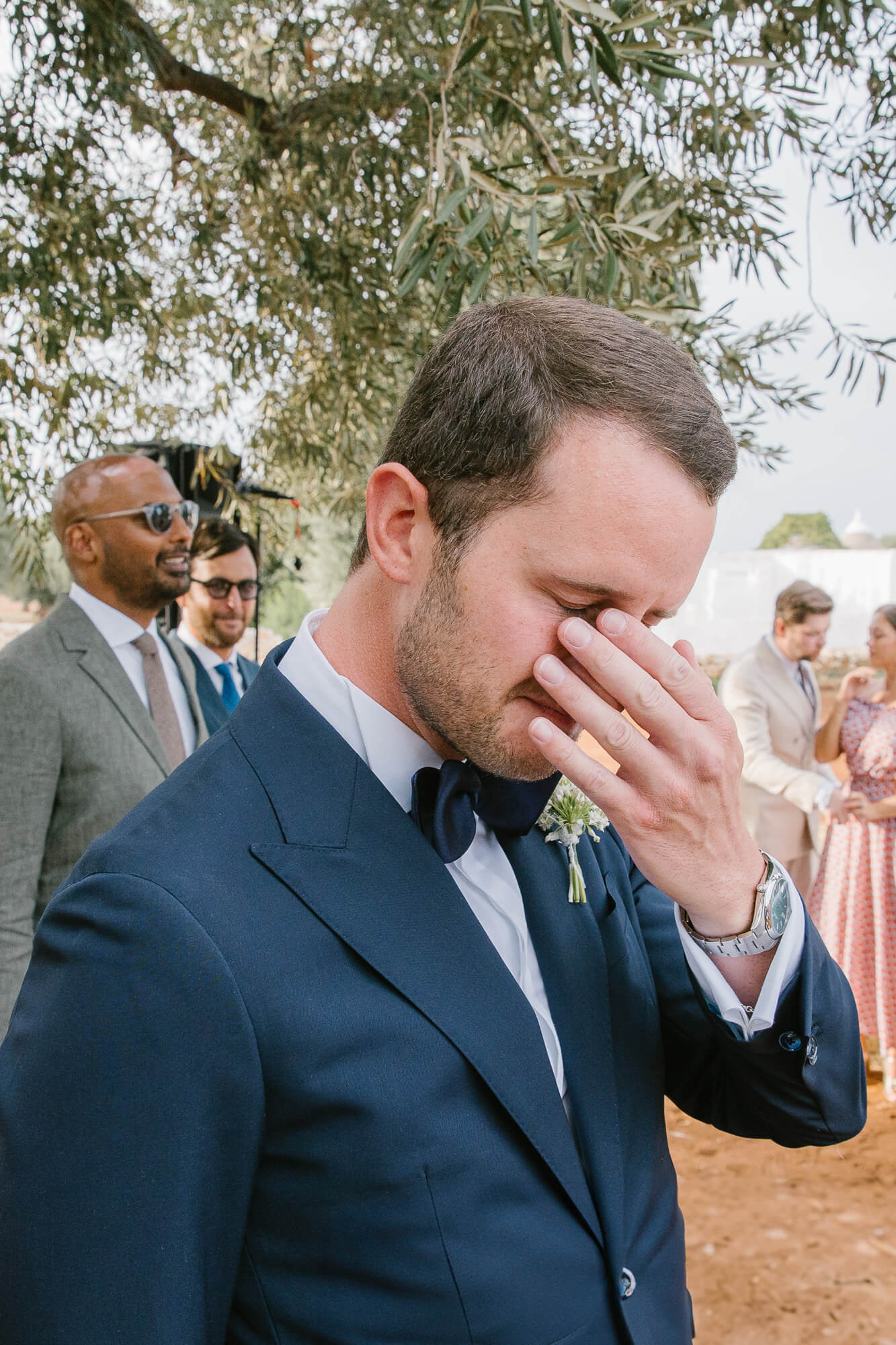 Emotional groom wiping a tear as the bride arrives