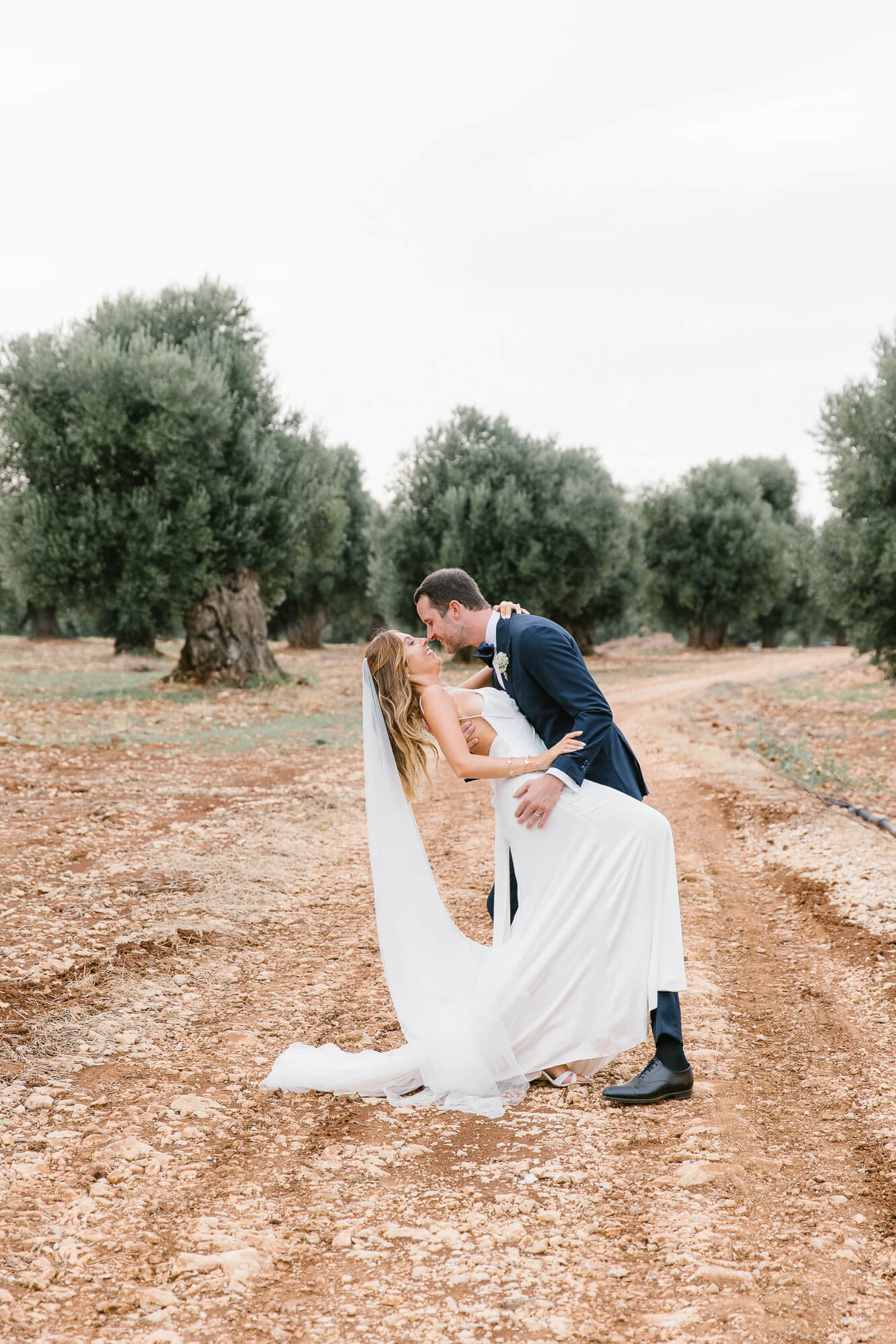 Groom dipping the bride among the olive trees
