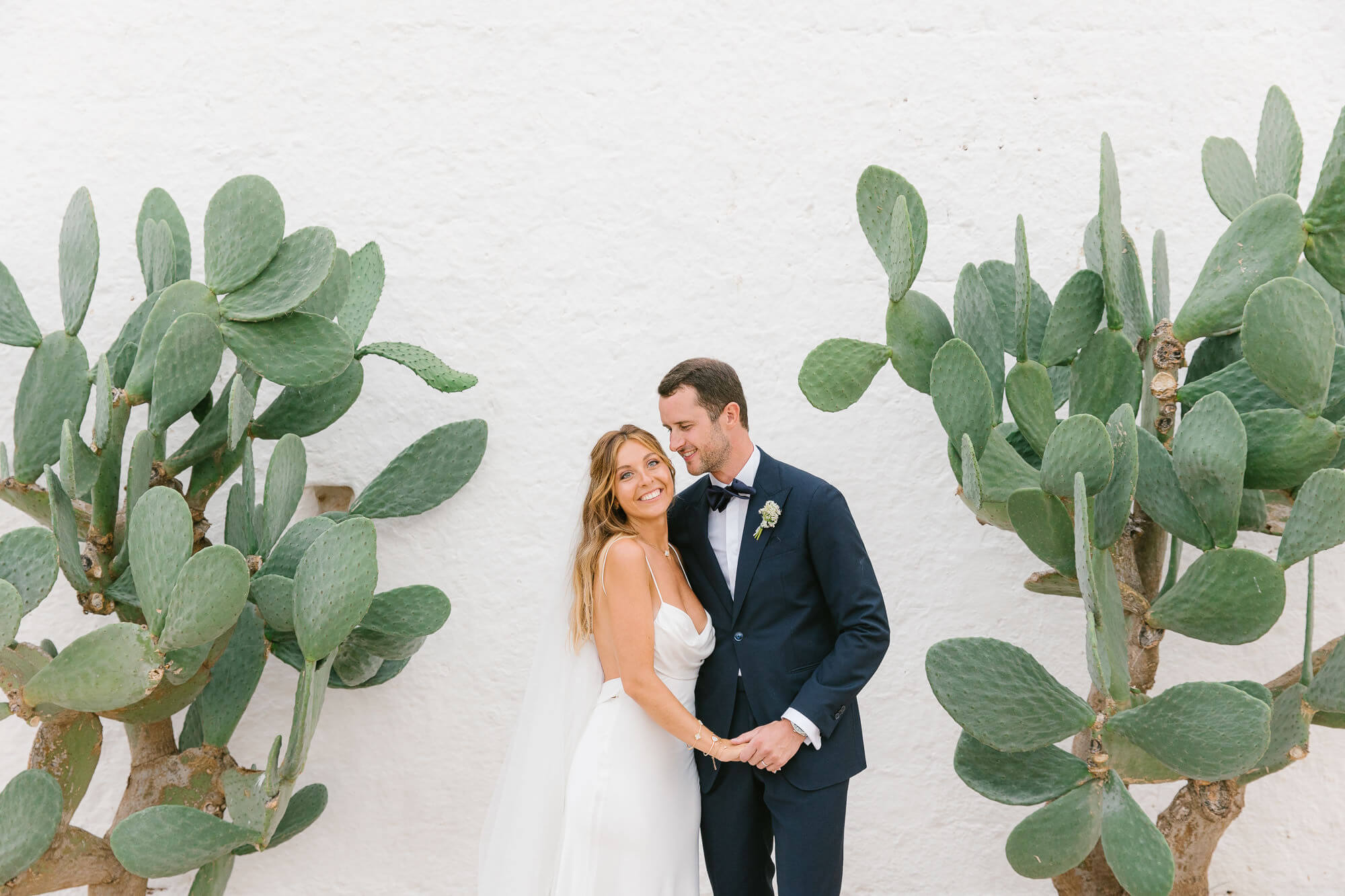Couple portrait against prickly pears and whitewashed walls at Masseria Mozzone