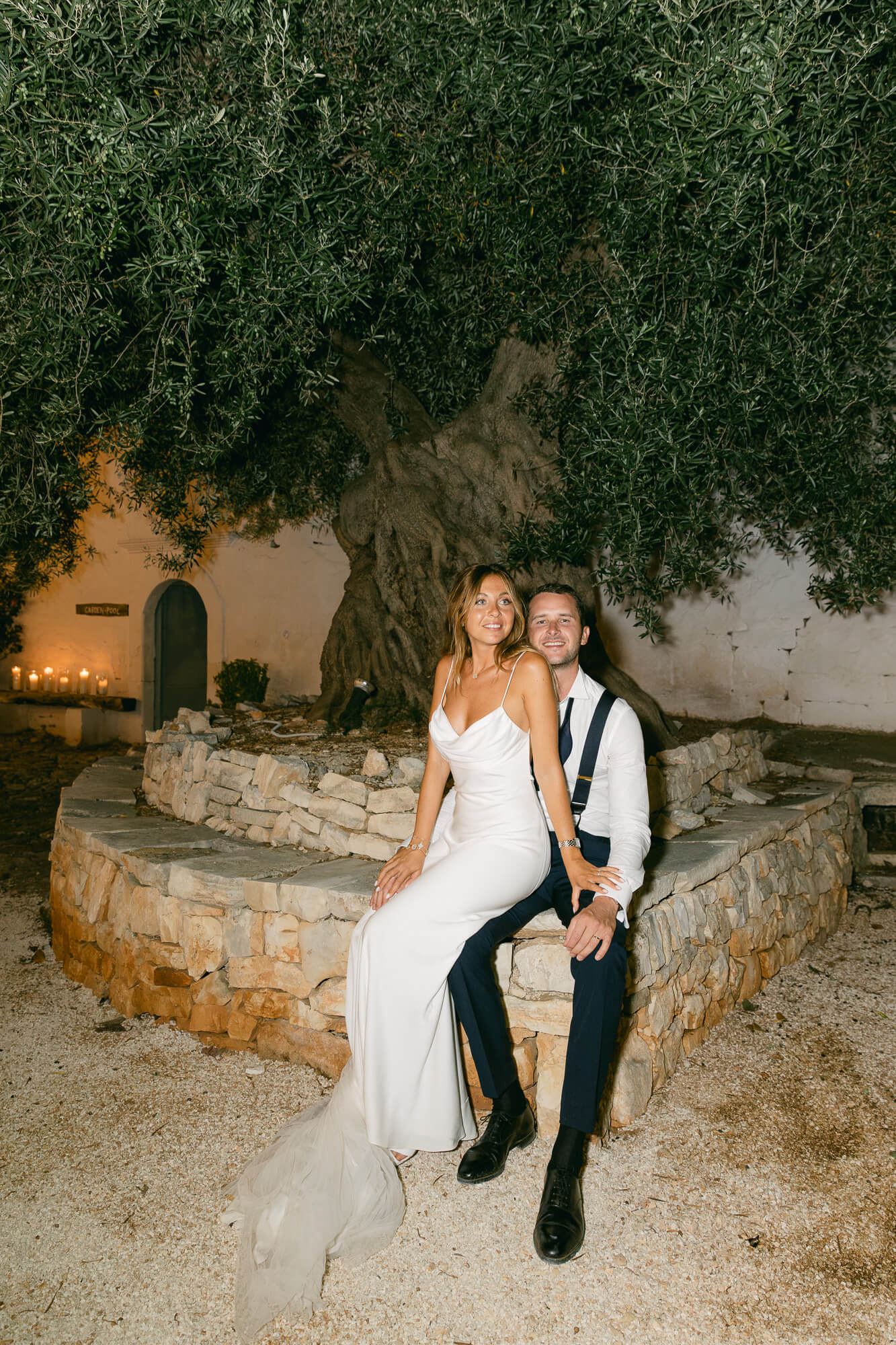 Night portrait of the newlyweds under an olive tree