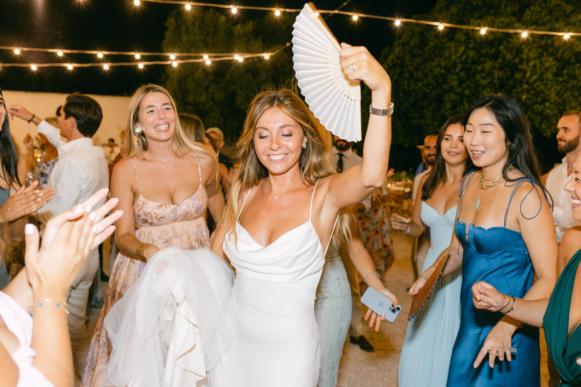 Bride laughing on the dance floor surrounded by friends