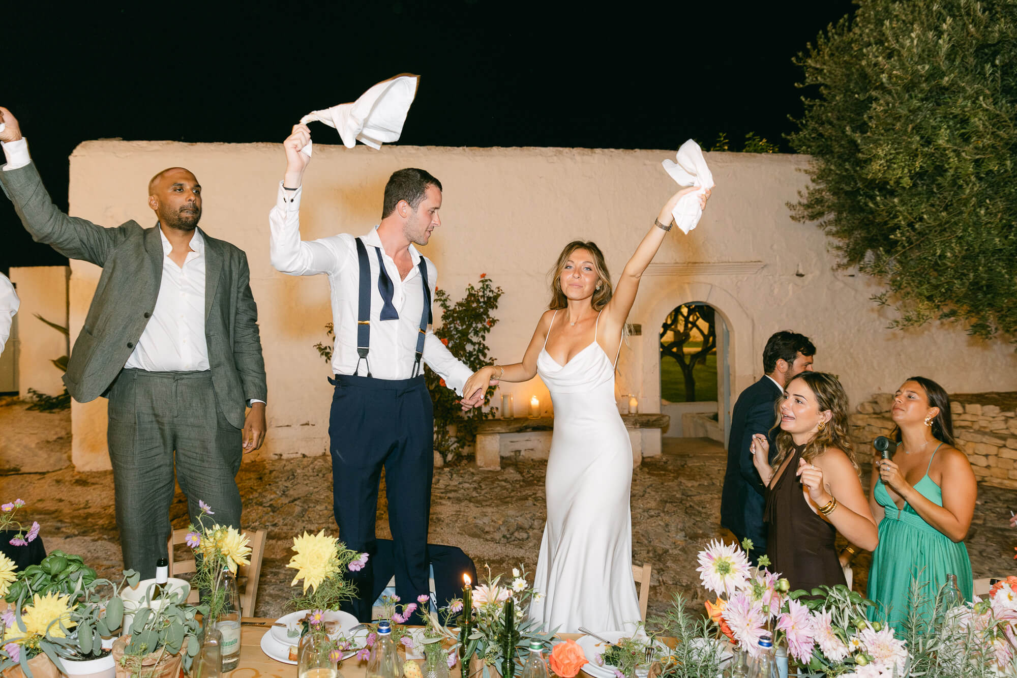 Guests swinging napkins with the bride and groom at dinner