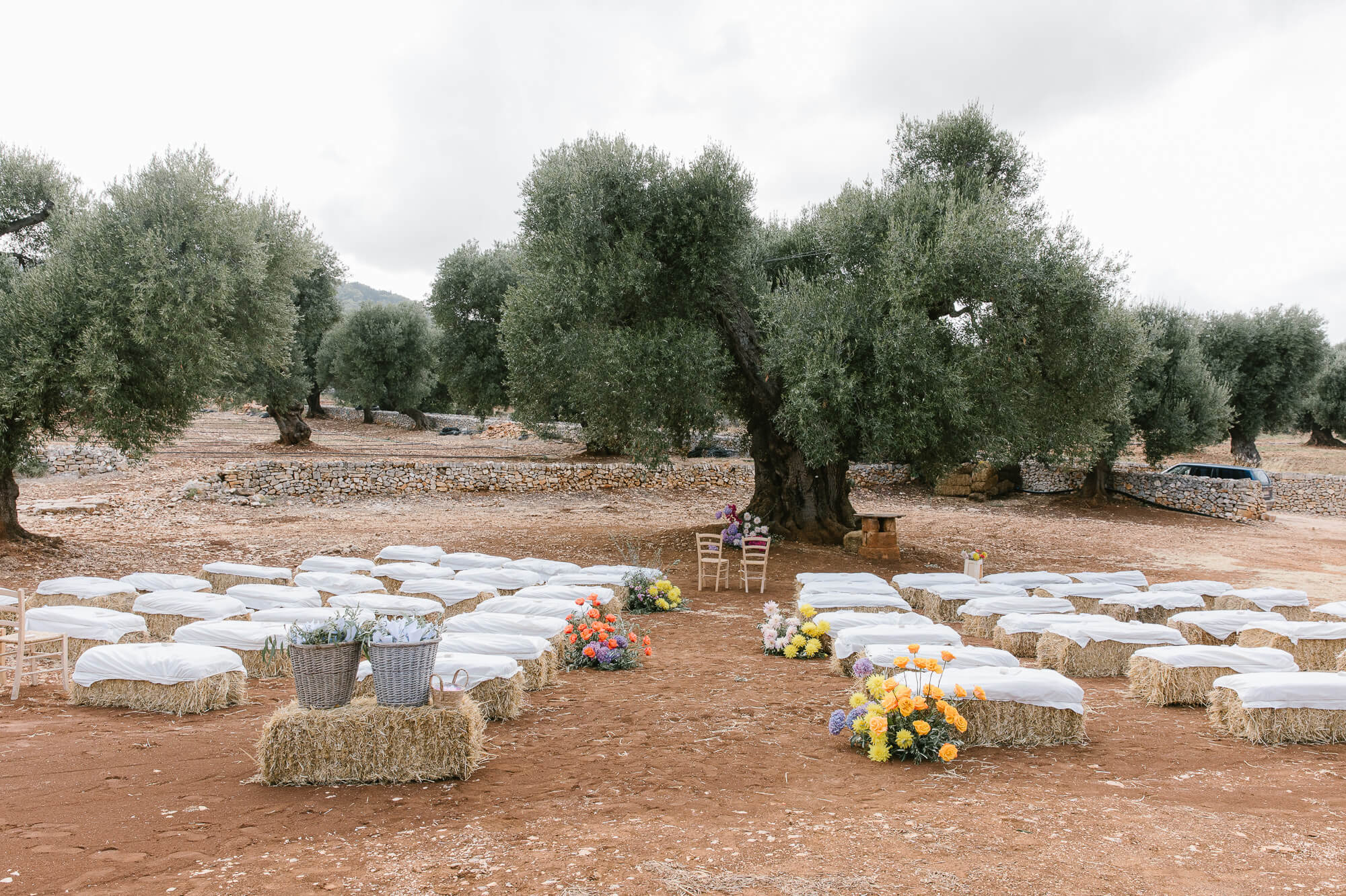 Olive grove ceremony with straw bale seating at Masseria Mozzone