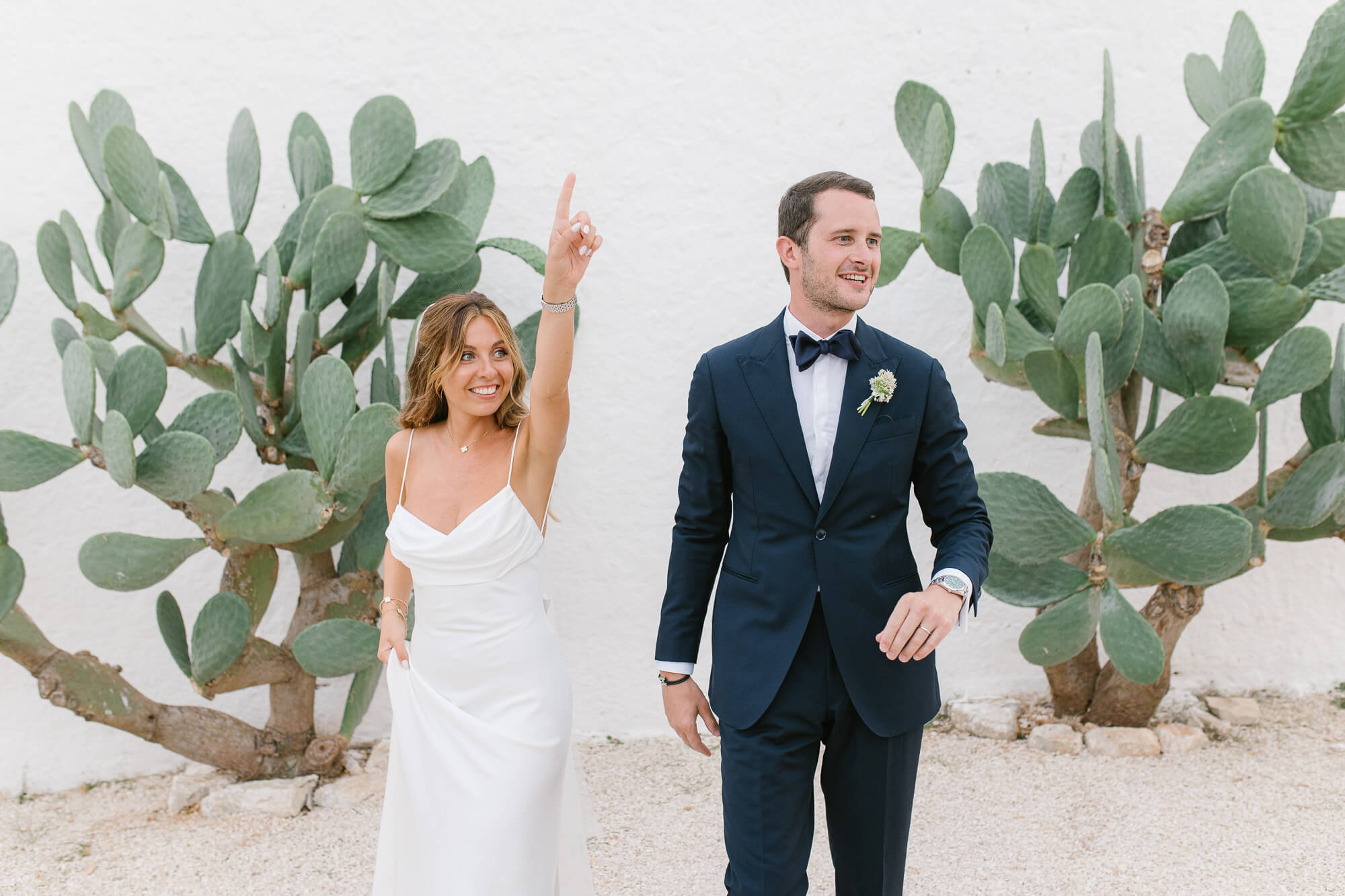 Bride and groom laughing between prickly pears at Masseria Mozzone